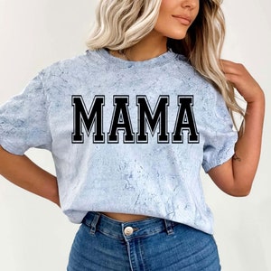 May include: A light blue t-shirt with a white marbled pattern. The shirt has a black block letter design that says "MAMA".