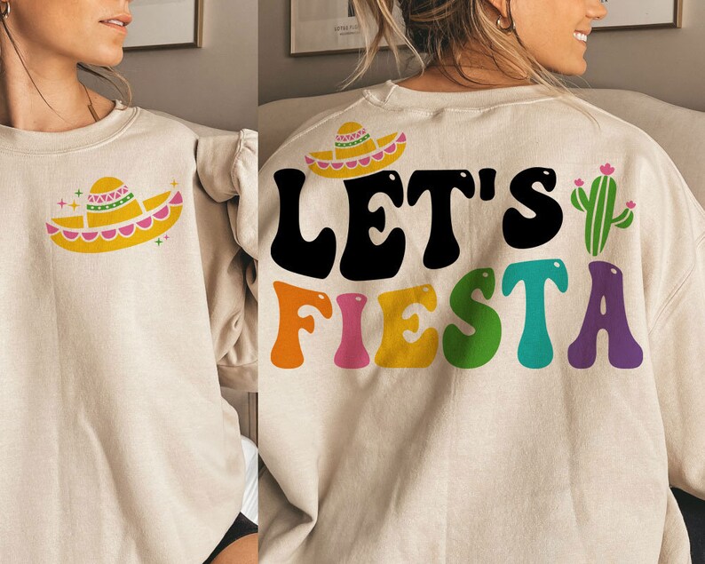 May include: A beige sweatshirt with a colorful "Let's Fiesta" graphic and a small sombrero design. The graphic features a cactus and colorful letters.