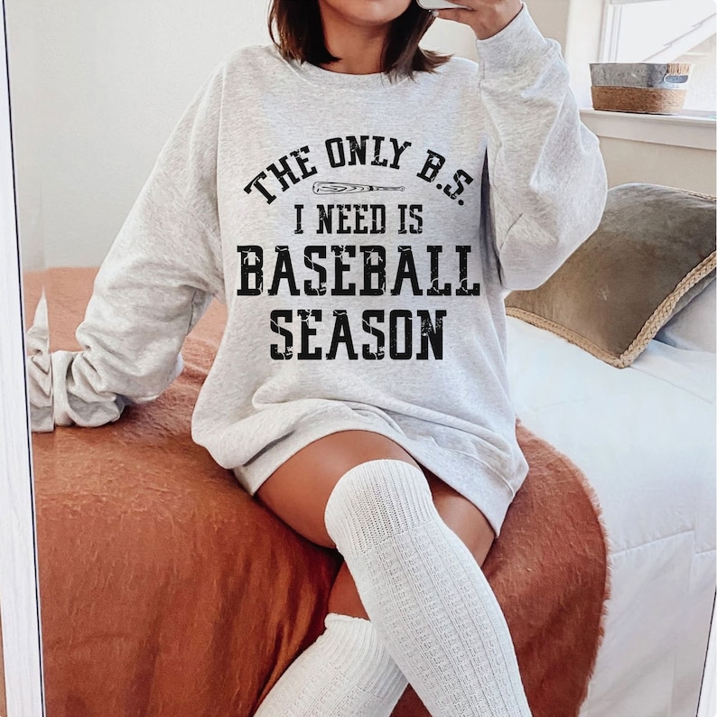 May include: A grey sweatshirt with the text "The only B.S. I need is baseball season" printed on it. A baseball bat graphic is included in the text.