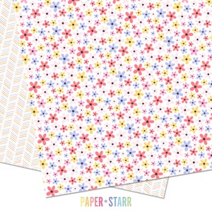 May include: A white background with a repeating pattern of small pink, yellow, blue, and red flowers. The flowers are scattered randomly across the background. There are also small black dots scattered throughout the background. The text "PAPER + STARR" is at the bottom of the image.
