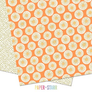 May include: A sheet of orange patterned paper with a white and green floral design. The paper is folded in half and the bottom edge is visible. The text "PAPER + STARR" is printed on the bottom edge of the paper.