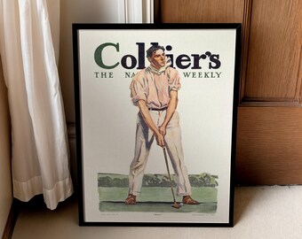 May include: Framed vintage print of a golfer in a light pink shirt and white pants, preparing to swing. The print is a cover from Collier's Weekly magazine. The title is in green and black lettering. The image is framed in a black frame.