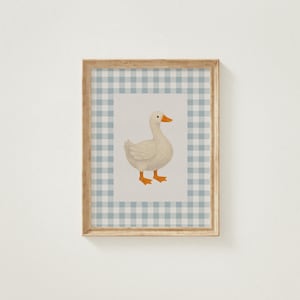 May include: Framed artwork featuring a white goose with orange feet and beak. The goose is centered on a light background, framed by a blue and white gingham pattern. The wooden frame adds a rustic touch to the artwork.