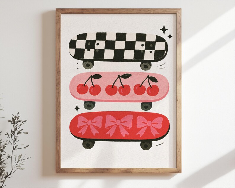 May include: A framed print featuring three colorful skateboards. The top skateboard has a black and white checkered pattern. The middle skateboard is pink with red cherries. The bottom skateboard is red with pink bows. The skateboards have black wheels.