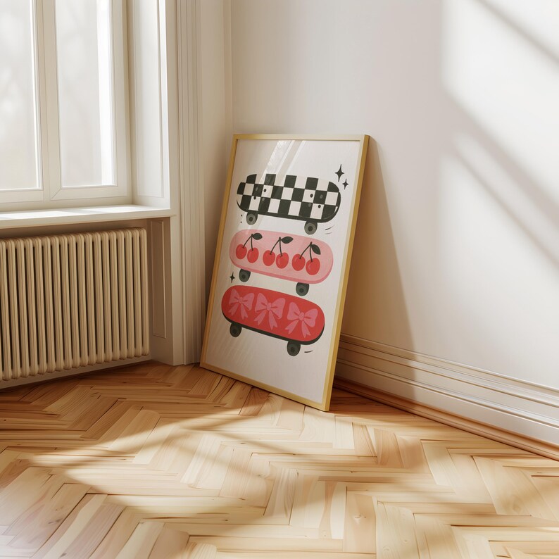 May include: A framed print featuring three skateboards with unique designs. The top skateboard has a black and white checkered pattern. The middle skateboard is pink with cherries. The bottom skateboard is red with bows.