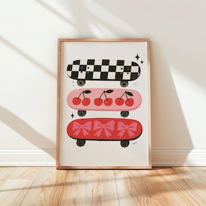 May include: A framed print featuring three skateboards with unique designs. The top skateboard has a black and white checkered pattern. The middle skateboard is pink with cherries. The bottom skateboard is red with pink bows. The print is displayed on a wooden floor.
