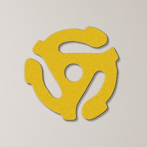 May include: A yellow vinyl record adapter symbol wall decor. The symbol is a stylized representation of a record adapter, a device used to play records on turntables. The symbol is mounted on a white wall in a room with a wooden floor and furniture.
