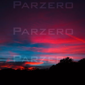 Könnte beinhalten: Ein lebendiger Sonnenuntergangshimmel mit roten, orangefarbenen und blauen Wolkenstreifen. Der Himmel wird von einer Reihe dunkler Bäume silhouettiert.