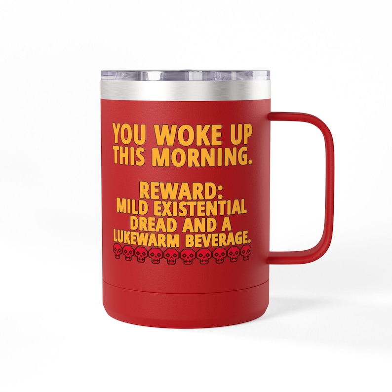 May include: A red stainless steel travel mug with a handle and a silver lid. The mug features yellow text that reads: YOU WOKE UP THIS MORNING. REWARD: MILD EXISTENTIAL DREAD AND A LUKEWARM BEVERAGE. A row of small red skull icons is printed below the text.