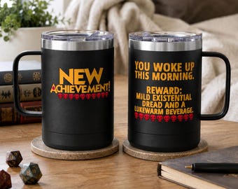 May include: Two black stainless steel mugs with handles and clear lids. The left mug features the yellow text "NEW ACHIEVEMENT!" above a row of red skulls. The right mug displays the yellow text "YOU WOKE UP THIS MORNING. REWARD: MILD EXISTENTIAL DREAD AND A LUKEWARM BEVERAGE." above a row of red skulls.