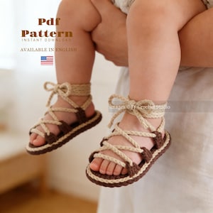 Puede incluir: Sandalias de bebé de ganchillo en marrón y beige, con un diseño de gladiador y correas entrecruzadas. Las sandalias se muestran en los pies de un bebé. La imagen incluye el texto "Pdf Pattern Instant Download Available in English".