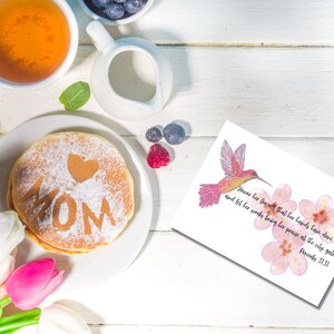 May include: A white card with pink flowers and a hummingbird illustration. The card has a quote from Proverbs 31:31: "Honor her for all that her hands have done, and let her works bring her praise at the city gate."