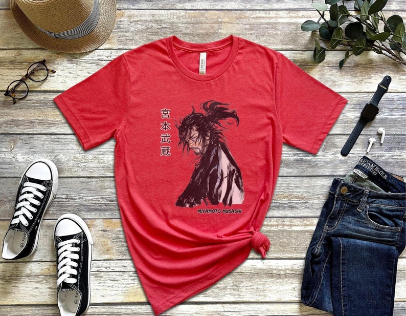 May include: Red t-shirt with a black and white illustration of a samurai warrior with the text "Miyamoto Musashi" and Japanese characters that read "日本 武蔵".