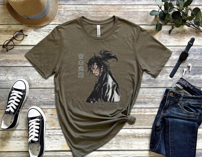 May include: A green t-shirt with a black and white illustration of a samurai warrior. The text "日本武道" is printed on the shirt. The text "MIYAMOTO MUSASHI" is printed below the illustration.