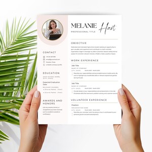 May include: A white resume template with a soft pink circular photo frame at the top left. The document features sections for contact, education, awards, objective, work experience, and volunteer experience with black text and lines.