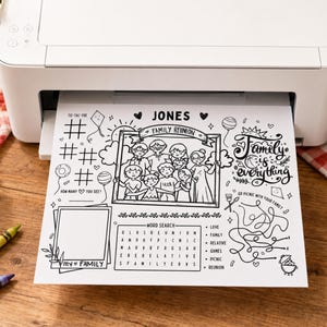 May include: A white printer outputting a black and white activity sheet titled Jones Family Reunion. The sheet features a central illustration of a family, a word search, a maze, a tic-tac-toe grid, and the text Family is everything.