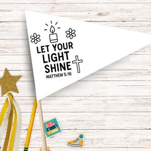 Könnte beinhalten: Ein weißes Wimpelbanner mit dem Text "LET YOUR LIGHT SHINE" und "MATTHEW 5:16" in Schwarz. Das Banner zeigt eine Kerze, Blumen und ein Kreuz. Das Banner befindet sich auf einem Holzstab, mit dekorativen Elementen drumherum.
