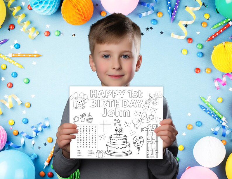 Puede incluir: Un ni&ntilde;o sostiene una p&aacute;gina para colorear blanca con el texto "HAPPY 1st BIRTHDAY John" en negro. La p&aacute;gina presenta ilustraciones de una tarta, globos y un laberinto. El fondo est&aacute; decorado con globos de colores, confeti y serpentinas.