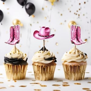 以下が含まれることがあります： ピンクの カウボーイ ブーツ と ピンクの カウボーイ ハット の トッパー で 飾られた カップケーキ が 3 つ あります。 カップケーキ は 白 と 黒 の フロ スティング で 飾られ て おり、 ゴールド の カップケーキ ライナー が 付い て い ます。