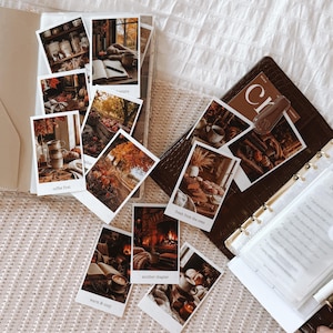 May include: A collection of rectangular photo prints featuring autumn-themed imagery, including scenes of pumpkins, fireplaces, coffee, and books. Each print has a white border and text captions like coffee first, fresh from the oven, and another chapter.