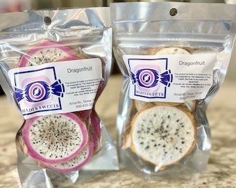 May include: Two clear plastic bags with white labels and the text "MADI'S SWEETS" and "Dragonfruit". The bags contain dried dragonfruit slices. The text on the labels includes information about the product being made in a home kitchen and not inspected by the Department of Health Services. The labels also include the company's contact information: Amarillo, Texas 79109, 806-433-3589.