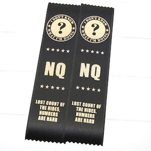 May include: Two black satin ribbons with gold text. Each ribbon features the phrase "I DON'T KNOW WHAT I'M DOING" around a question mark, the letters "NQ", and the text "LOST COUNT OF THE HIDES, NUMBERS ARE HARD".