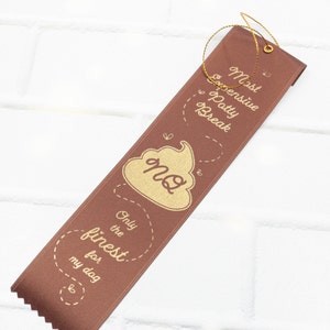 May include: Brown ribbon with gold text and a gold poop emoji. The text reads "Most Expensive Potty Break Only the Finest for my dog".