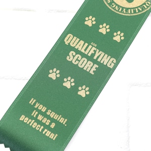 May include: Green ribbon with gold text that reads "for qualifying score" and "if you squint, it was a perfect run!" with paw prints.