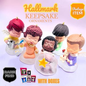 Könnte beinhalten: Fünf Hallmark Keepsake Ornamente mit cherubartigen Figuren und verschiedenen Accessoires, darunter eine silberne Gießkanne, ein blauer Vogel, ein gelber Stern und ein kleiner Hund, begleitet von vier kleinen rechteckigen Produktboxen.