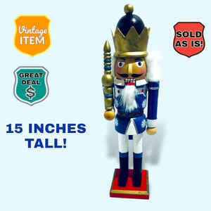 Może przedstawiać: Figurka do dziadków do orzechów w stylu vintage, 38 cm wysokości, ze złotą koroną, wąsami i niebiesko-białym mundurem. Figurka ma czerwoną podstawę i trzyma złoty kij. Obraz zawiera tekst "Vintage Item" i "Great Deal".