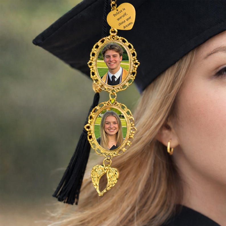 Pu&ograve; includere: Ciondolo per nappa di laurea dorato con due cornici ovali per foto e un ciondolo a forma di cuore. Le cornici contengono foto di un giovane uomo e una giovane donna. Il ciondolo a forma di cuore riporta la scritta "Believe in yourself, chase your dreams."