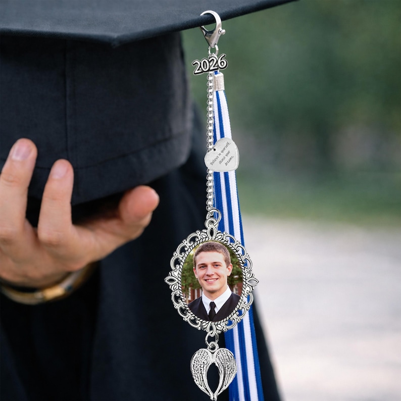 Pu&ograve; includere: Un ciondolo per nappa di cappello di laurea con una foto in una cornice d'argento decorativa. Il ciondolo include un cuore d'argento con la scritta "Believe in yourself, chase your dreams" e un ciondolo ad ala d'angelo d'argento.