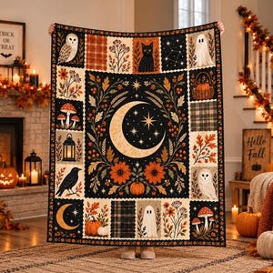 May include: A rectangular throw blanket featuring a central crescent moon and star motif surrounded by panels of autumn-themed illustrations including owls, a black cat, ghosts, pumpkins, mushrooms, a lantern, a raven, and floral patterns.
