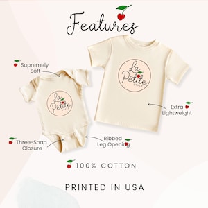 May include: Two cream-colored shirts with a cherry logo that says "La Petite Style". The smaller shirt is a bodysuit with a three-snap closure. The larger shirt is a t-shirt. Both shirts are made of 100% cotton and are printed in the USA.