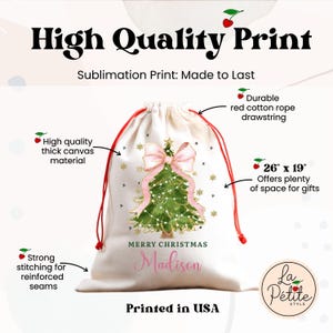 K&ouml;nnte beinhalten: Ein wei&szlig;er Geschenksack aus Segeltuch mit Kordelzug, 66 cm mal 48 cm gro&szlig;. Der Sack zeigt eine gr&uuml;ne Weihnachtsbaum-Illustration mit einer gro&szlig;en rosa Schleife, goldenen Schneeflocken und dem Text Merry Christmas Madison. Rote Baumwollkordel.