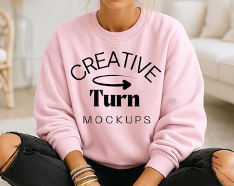 Könnte beinhalten: Hellrosa Sweatshirt mit dem schwarzen Schriftzug "CREATIVE Turn MOCKUPS". Das Sweatshirt hat lange Ärmel und einen Rundhalsausschnitt. Das Model trägt eine schwarze Jeans und goldene Armbänder.