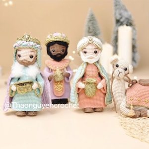 May include: Three crocheted figures representing the Three Wise Men, each wearing detailed robes and crowns or turbans, accompanied by a small crocheted camel. The figures hold miniature gold-colored vessels. Text reads PDF Pattern @Thaonguyencrochet.