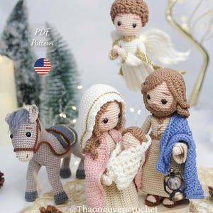 Könnte beinhalten: Ein Häkel-Krippenset mit Figuren von Maria, Josef und dem Jesuskind, begleitet von einem Esel und einem Engel. Die Figuren sind aus Garn in Beige, Rosa, Blau und Weiß gefertigt, wobei Josef eine kleine Laterne in der Hand hält.