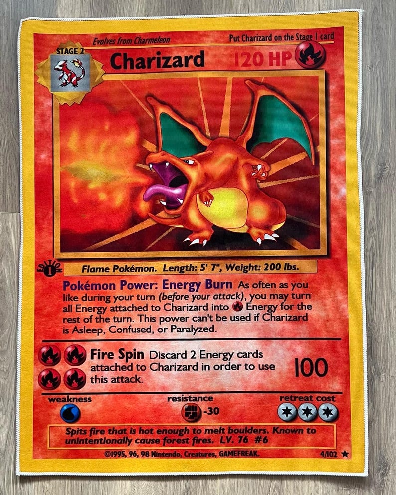 Puede incluir: Una carta coleccionable con Charizard, un Pok&eacute;mon de tipo fuego del Juego de Cartas Coleccionables Pok&eacute;mon. La carta es naranja, roja y amarilla con una imagen de Charizard escupiendo fuego. La carta tiene un poder llamado "Quemadura de energ&iacute;a" y un ataque llamado "Giro de fuego". La carta es del set 1995, 96, 98 Nintendo, Creatures, GAMEFREAK y es n&uacute;mero 4/102.