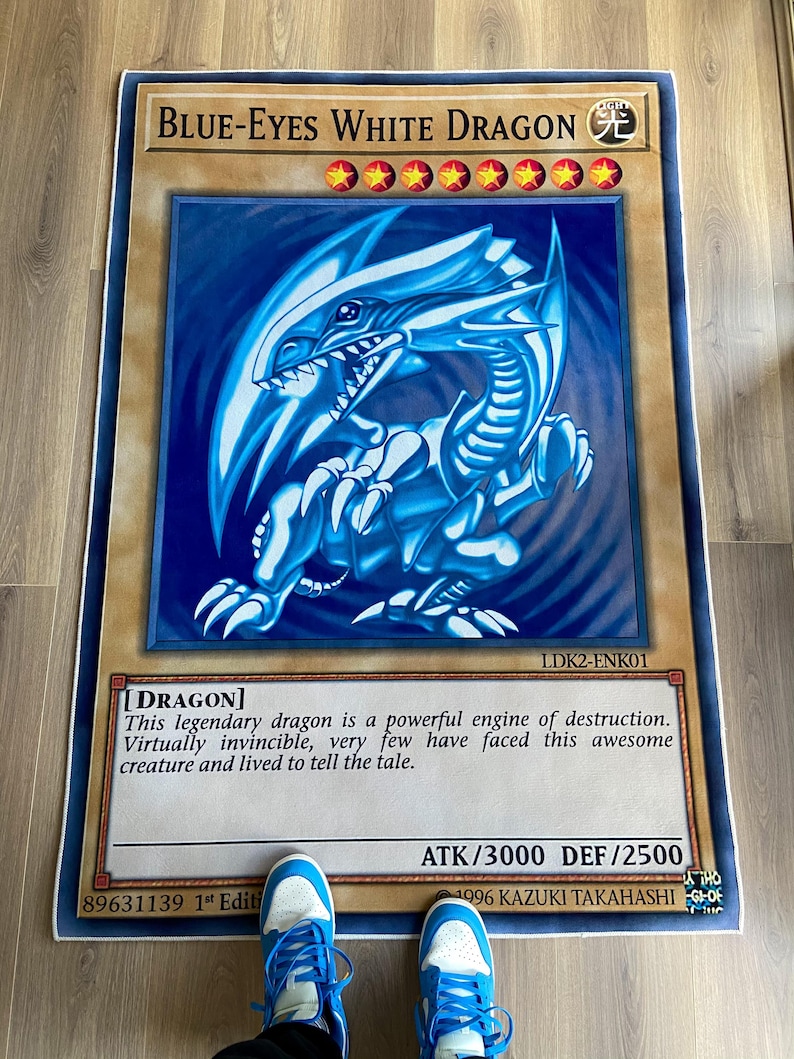 Puede incluir: Una carta de juego de rol "Drag&oacute;n Blanco de Ojos Azules" con un fondo azul claro. La carta representa un drag&oacute;n blanco con ojos azules sobre un fondo azul claro. El texto de la carta dice "Drag&oacute;n Blanco de Ojos Azules" y "[DRAGON]". La carta tambi&eacute;n incluye el texto "Este legendario drag&oacute;n es un poderoso motor de destrucci&oacute;n. Pr&aacute;cticamente invencible, muy pocos se han enfrentado a esta incre&iacute;ble criatura y han vivido para contarlo."