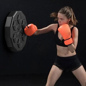 May include: A woman in orange boxing gloves and black sportswear practices boxing with a black, hexagonal, wall-mounted punching target. The target has six hexagonal pads and a central star design.