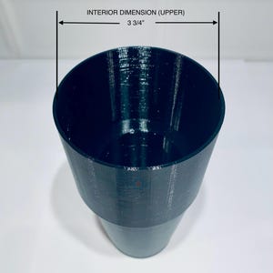 May include: A dark teal-colored cup with a textured surface. The upper interior dimension is 3 3/4 inches. The cup has a wide opening that tapers down to a narrower base. The cup is sitting on a white surface.