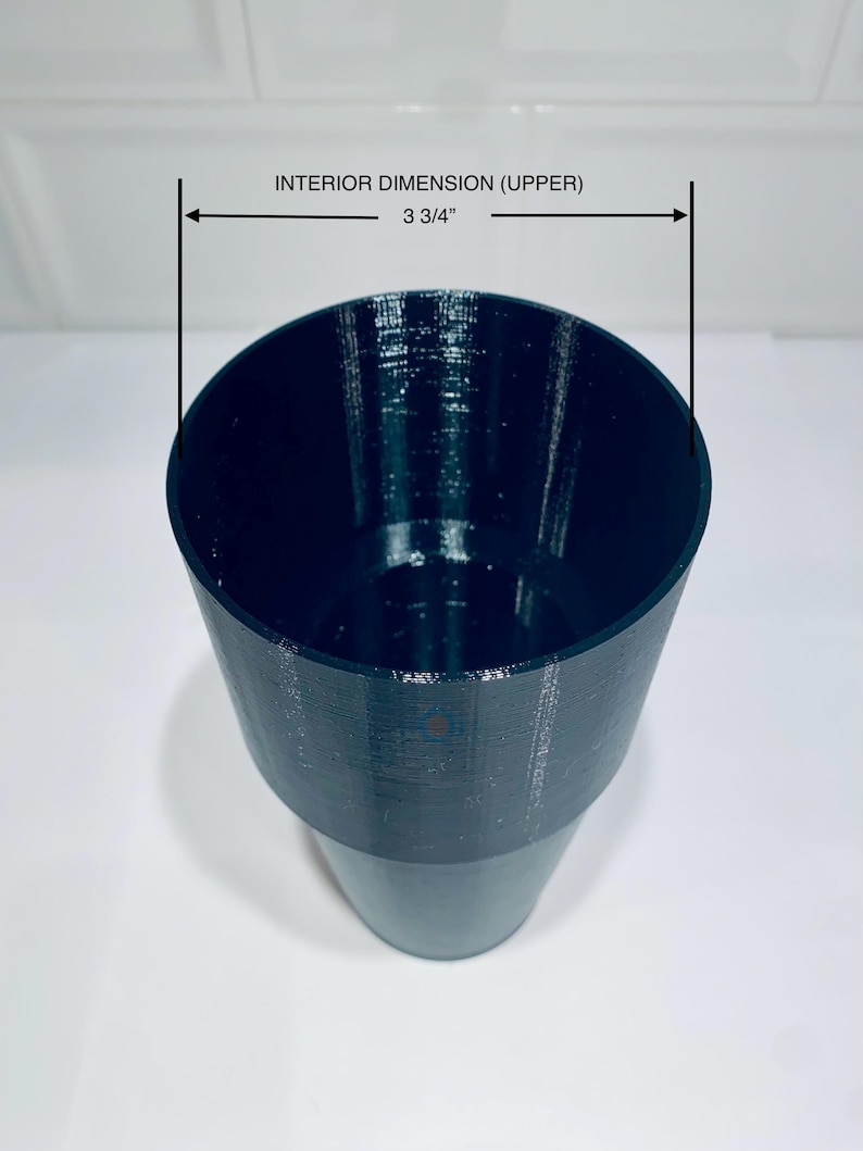 May include: A dark teal-colored cup with a textured surface. The upper interior dimension is 3 3/4 inches. The cup has a wide opening that tapers down to a narrower base. The cup is sitting on a white surface.