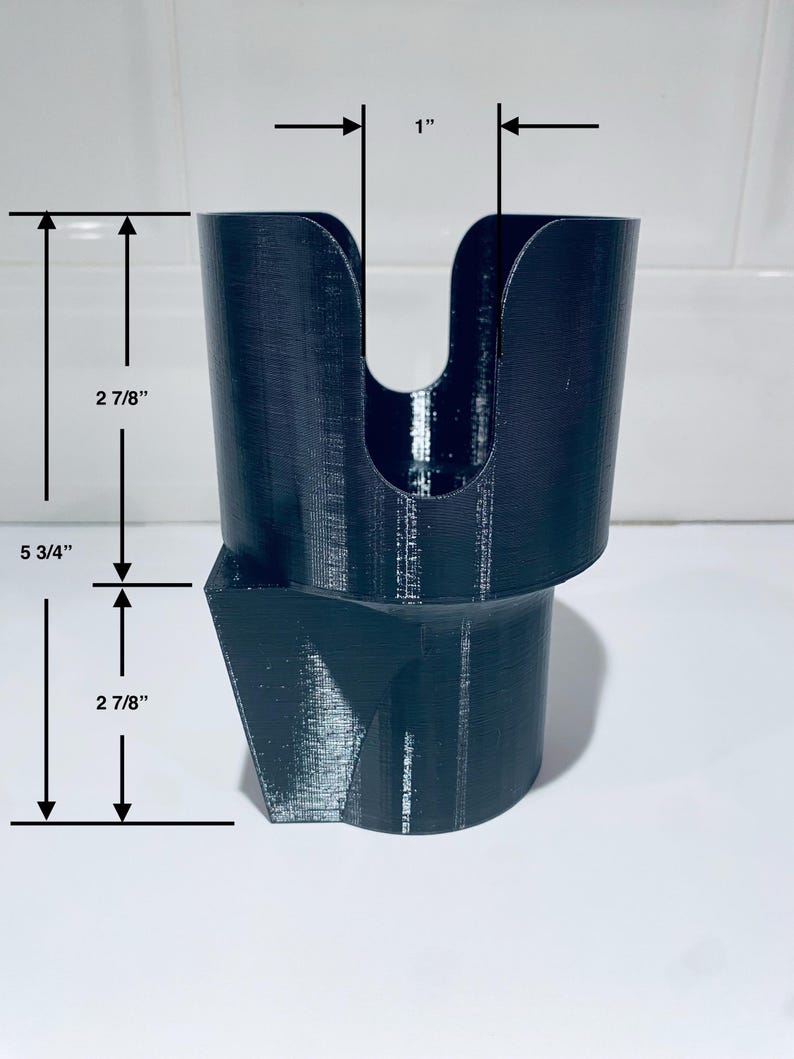 May include: Black, 3D-printed cup holder with a unique design. The holder is 5 3/4 inches tall, with a top opening of 1 inch. The upper cup section is 2 7/8 inches tall, and the base is also 2 7/8 inches tall. The holder has a distinctive angled base.