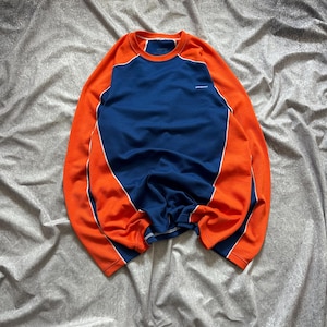 Puede incluir: Una sudadera azul y naranja de manga larga con ribete blanco. La sudadera tiene cuello redondo y un pequeño logotipo en el pecho. Las mangas y los hombros son naranjas, mientras que el torso es azul.