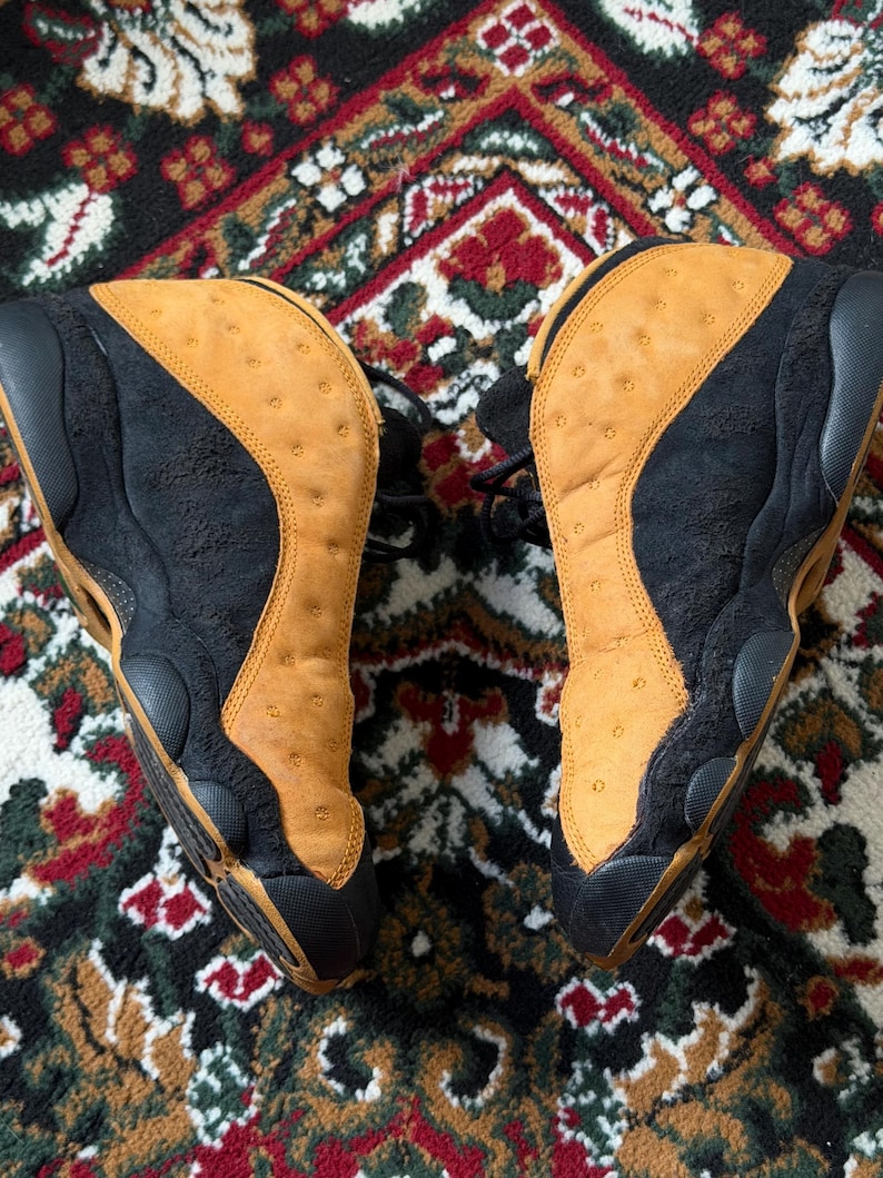 Op de afbeelding: Paar zwarte en bruin-gele sneakers. De schoenen hebben een bruin-geel bovenwerk met een geperforeerd patroon en zwarte details. De zolen zijn zwart en de sneakers zijn geregen.