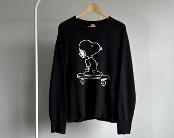 Sudadera KAWS Peanuts Snoopy en patineta, color negro, talla M