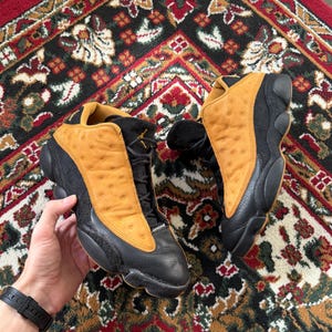 Op de afbeelding: Een witte keramische mok met een zwart handvat en de tekst "But First, Coffee" in een zwarte, vette letter. De mok staat op een wit oppervlak.