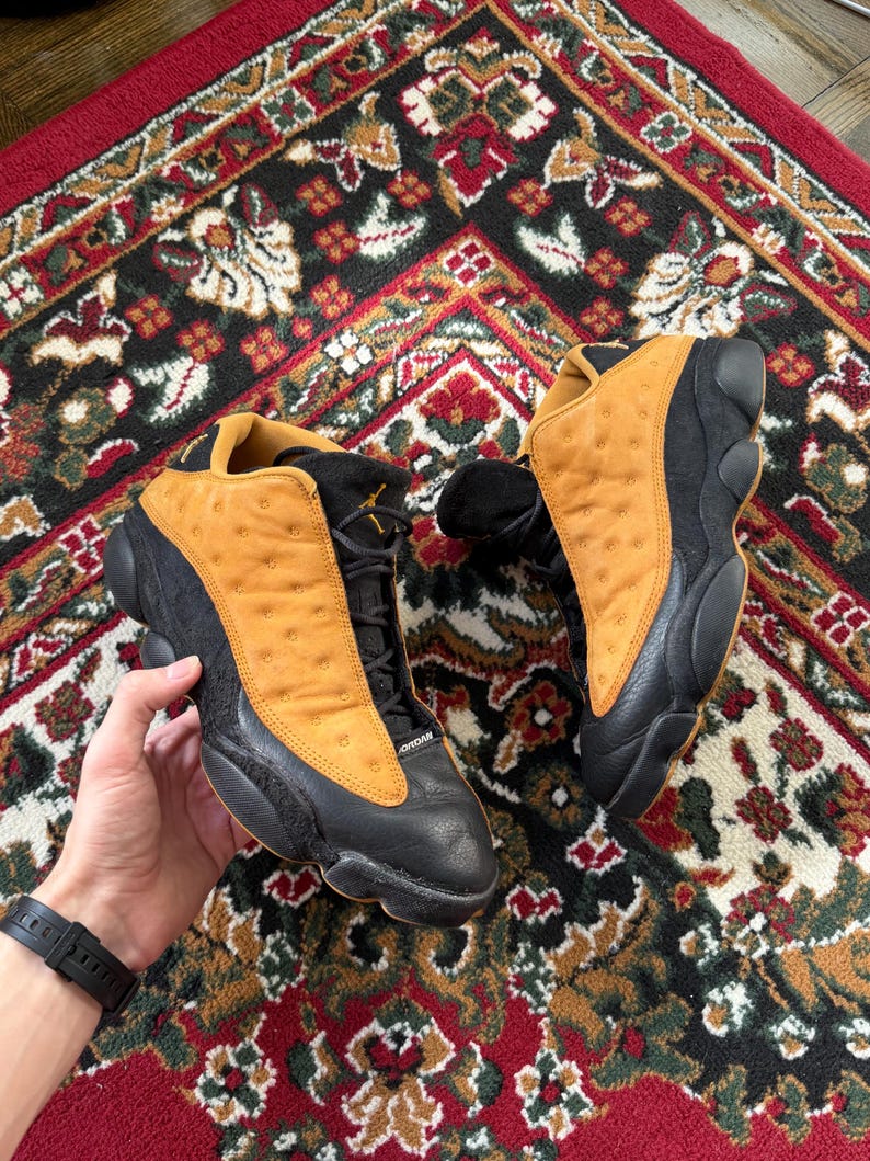 Op de afbeelding: Een witte keramische mok met een zwart handvat en de tekst "But First, Coffee" in een zwarte, vette letter. De mok staat op een wit oppervlak.