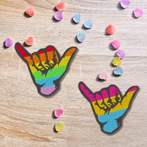 Pode incluir: Dois patches bordados com cores do arco-íris em forma de mão fazendo o sinal shaka, para passar a ferro.